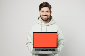 Young programmer happy fun man wear mint hoody hold use work on laptop pc computer with blank...