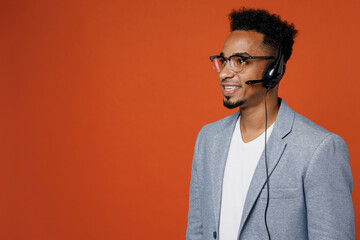Side view happy employee operator business man in set microphone headset for helpline assistance work at call center office look aside on workspace area isolated on plain red orange background studio. - obrazy, fototapety, plakaty
