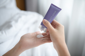 Close up of women applying body lotion cream on hand.