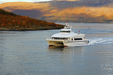 Catamaran ship in a fjord with rocky shores in autumn in Norway