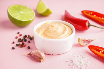 Bowl of tasty chipotle sauce on pink background