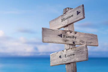 home family love text quote on wooden signpost crossroad by the sea