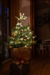 Christmas background with illuminated tree: decorated  blue spruce against a window in an apartment in Valencia, Spain. Copy space.