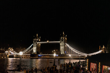 London Bridge or tower Bridge at night with the lights on and the River Thames below.