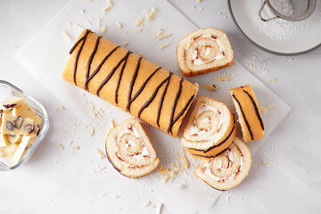 Delicious sponge cake roll and bowl with chocolate on white table