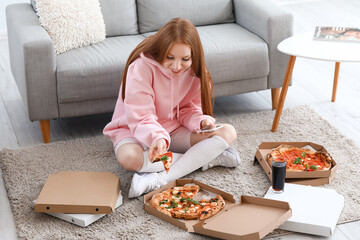 Young woman with tasty pizza and mobile phone at home