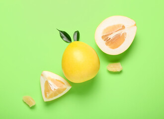 Whole and cut sweet pomelo fruit on green background