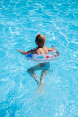 Child girl learn to swim with an inflatable ring in the pool