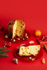 Plates with cut Panettones and Christmas decor on red background