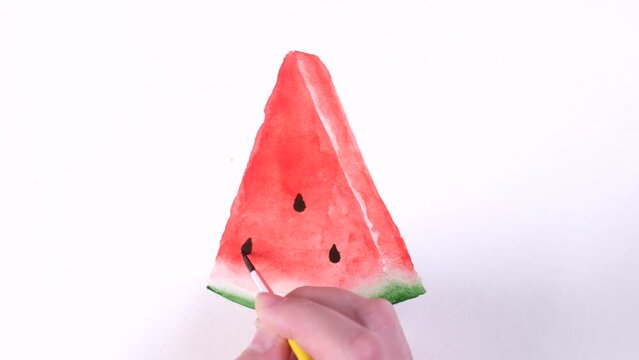 A woman's hand draws a piece of watermelon with watercolors