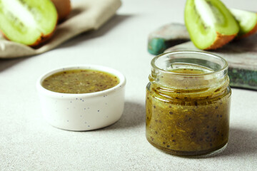 Homemade kiwi jam in a jar and kiwi slyces on concrete background with copy space