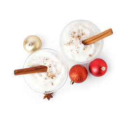 Glasses of tasty eggnog cocktail and Christmas balls on white background