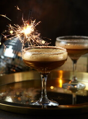 Espresso martini cocktail with sparkler on golden tray