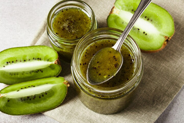 Homemade kiwi jam in a jar and kiwi slyces on concrete background with copy space