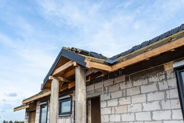 Ceramic tiles laid in packages on the roof on battens, visible concrete pillars at the entrance to the house.