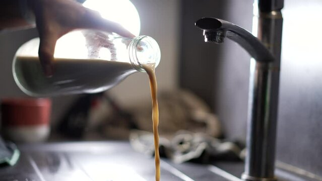 Pouring Old Milk Into Kitchen Sink. Hand Throwing Away Spoiled Food