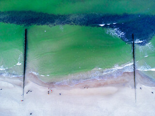 Snowy beach at Baltic sea in winter. Tourism in Poland. Aerial view of nature seashore and walking people.