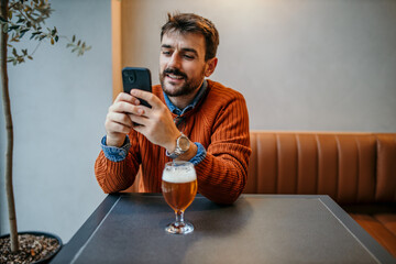 Portrait of a young freelancer on a break at a modern restaurant. Looking at the phone and having a drink.