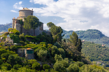 Fototapeta na wymiar Brown Castle surrounded by green olive trees and plants in the middle of the summer. Castello Brown is a historic house museum located high above the harbour of Portofino, Italy.