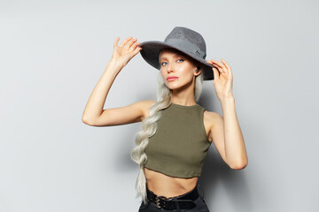 Obraz na płótnie Canvas Studio portrait of happy pretty blonde girl with wireless earphones into ears adjusts her hat, on white background.