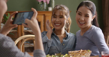 Small girl group party asia people busy talk smile eat brunch food drink. Young woman fun happy hour meal shoot photo of dish plate salad bowl on table post ig reel story app in vegan cafe bar shop.