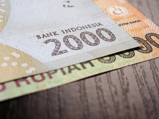 Obraz premium Indonesian banknotes lie on dark surface of office table. Fragment of 2000 rupiah note. Illustration on theme of economics or banking. Money of Indonesia. News about exchange rate or inflation. Macro