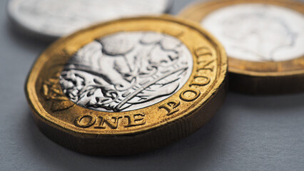 British coins lie on gray surface. One pound sterling coin closeup. Economy and money. Bank of England. UK currency and treasury. Pound illustration. Macro