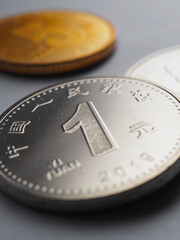 Translation: People's Bank of China, one yuan. PRC coins lie on light surface. 1 yuan coin close up. Economy, finance and bank. Money and business. Chinese yuan renminbi. Vertical illustration. Macro