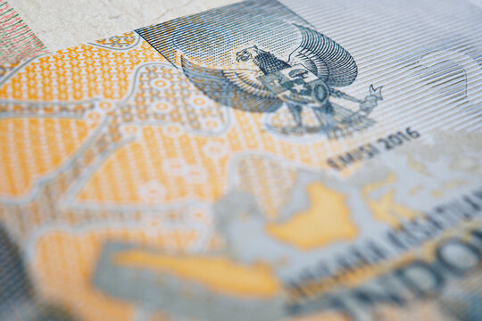 Indonesian money. Fragment of 2000 rupiah banknote. Photo is partially blurred, focus on head of Garuda bird. Emblem of Indonesia. Economy or finance background. Bank and credit. Macro