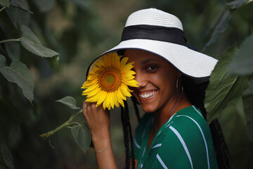 stylish young joyful woman in a hat in a field with sunflowers