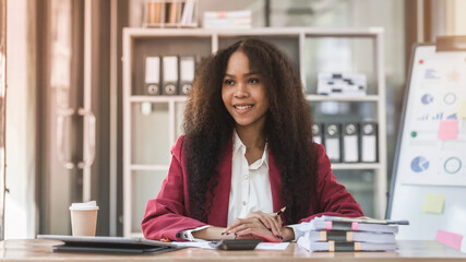 Young african american businesswoman red suit working at desk and using digital laptop in the modern office. Start up SME worker concept.