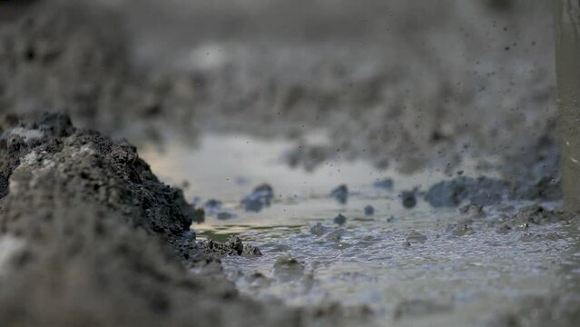 Worker using power tool, vibrator, compactor, for compacting fresh liquid concrete in close up slow motion view.