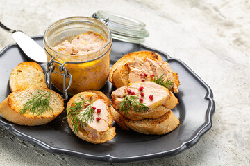 Close-up of plate with baguette toast with foie gras pate, directly above. Food product made of the liver of a duck or goose,  in a glass jar. Decorated with red pepper and dill. - obrazy, fototapety, plakaty