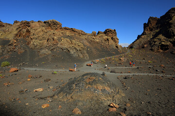 Leute Wandern im Vulkankrater der El Cuervo auf der Kanareninsel Lanzarote bei strahlend blauem Himmel
