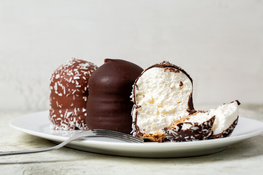 Moretti or negretti dessert. Soft meringue made of whipped egg white and sugar, waffle base, covered with chocolate or cocco. White background.