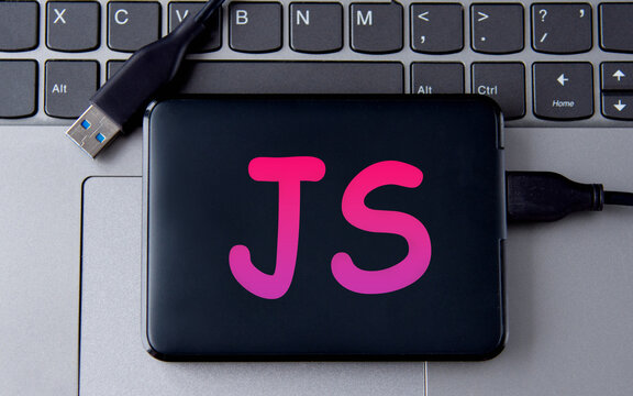 JS - acronum on an external drive in gray letters on the background of a laptop