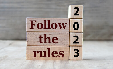 FOLLOW THE RULES 2023 - words on wooden blocks on gray background