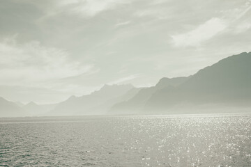 seascape with light reflection on the surface with mountain and blue sky as background
