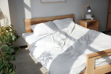 Large comfortable bed with soft pillows and blanket indoors
