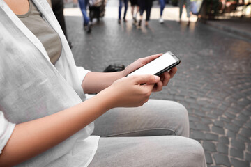 Young woman with smartphone outdoors, closeup view
