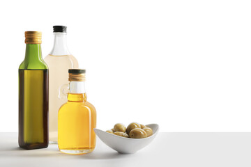 Fototapeta na wymiar Bottles of different cooking oils and olives on white background, space for text