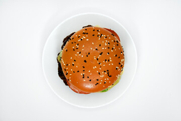 Double meat burger with vegetables on a white background. Delicious cheeseburger on a plate. Meat fast food. A large hamburger with a double cutlet.