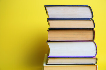 Collection of hardcover books on yellow background, space for text