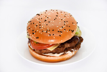 Double meat burger with vegetables on a white background. Delicious cheeseburger on a plate. Meat fast food. A large hamburger with a double cutlet.