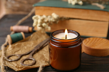 Burning scented candle, book and flowers on wooden table, closeup