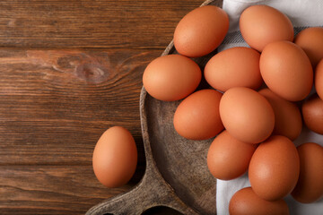 Raw brown chicken eggs on wooden table, flat lay. Space for text