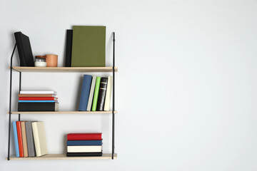 Shelves with many hardcover books on white wall. Space for text