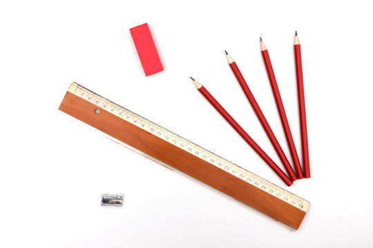 Symbol for school and education. Used wooden colored pencils isolated on white background together with red eraser and a ruler. 