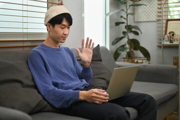 Young asian man making video call to friends or relatives, enjoying pleasant conversation