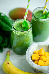 From above view of smoothie with banana, mango, spinach on wooden table. Healthy food. Vegetarian